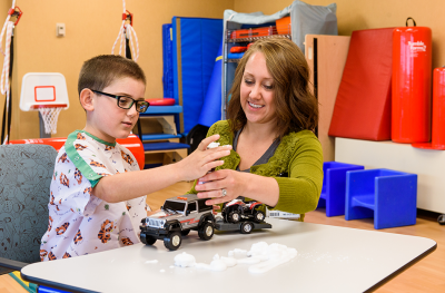 Boy building cars with woman in rehab