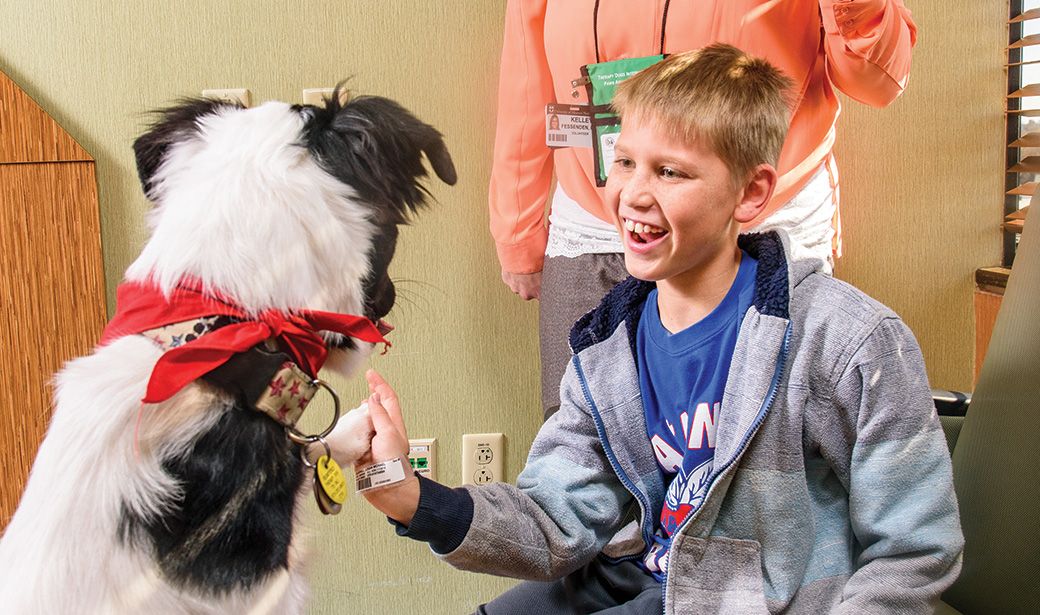 Logan Gladhill plays with Trooper at Children’s Hospital. Volunteers with certified therapy dogs visit MU Health Care patients regularly. 