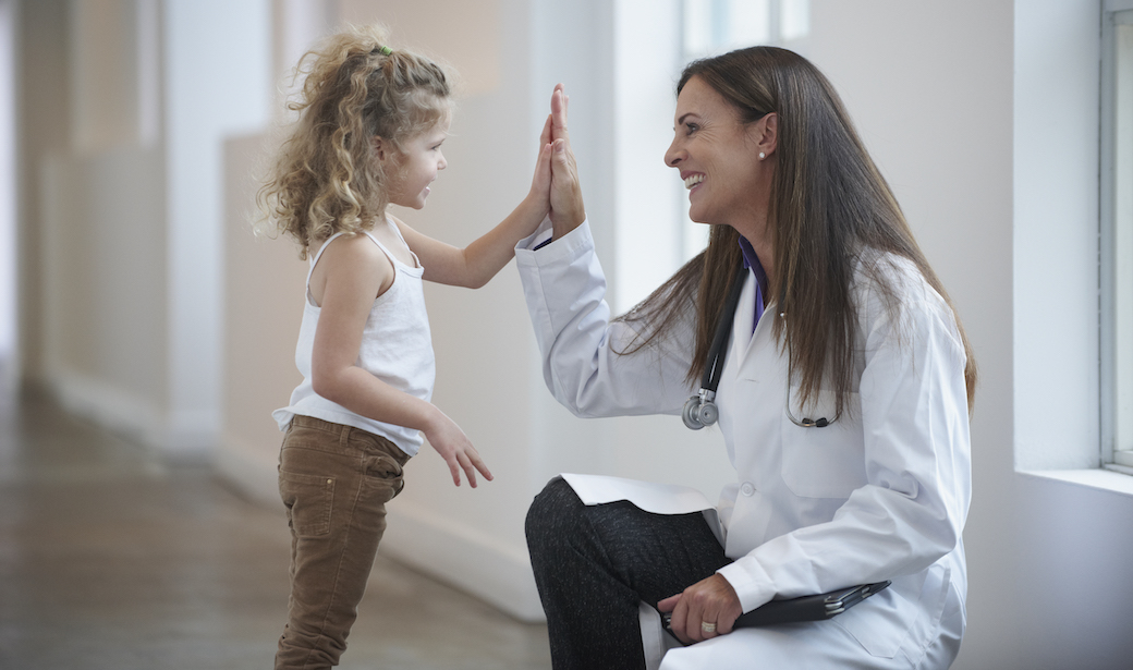 Pediatrician high-fiving a young girl
