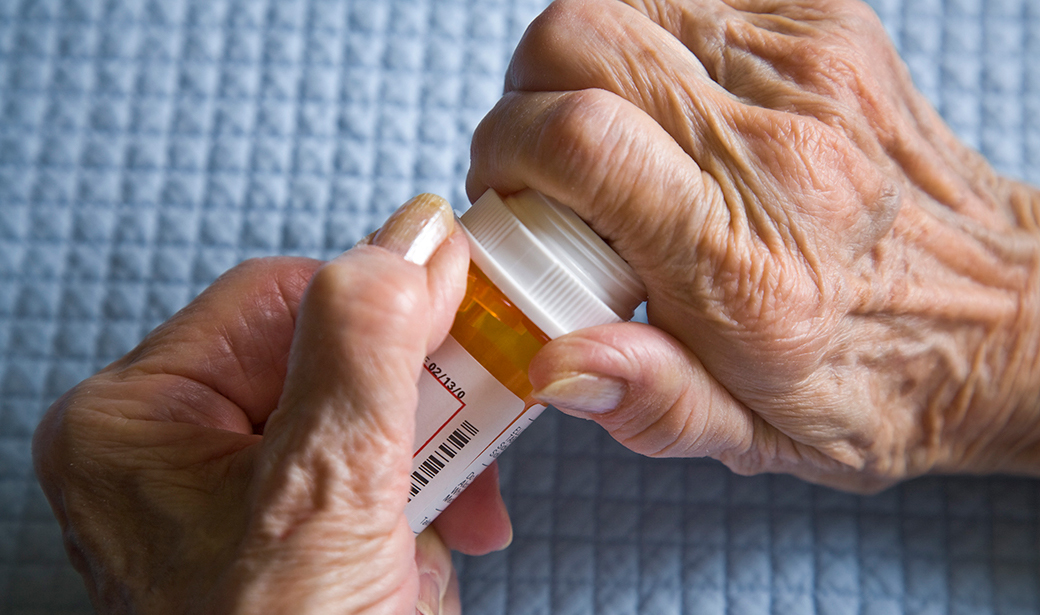 elderly person opening a pill bottle