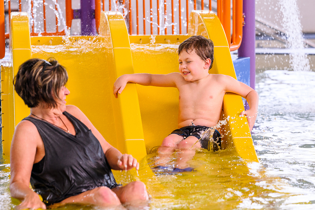 A mother and son playing on a water slide.