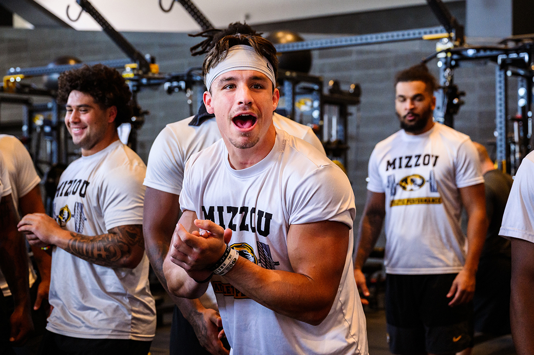 Logan Muckey flexing in the weight room with teammates.