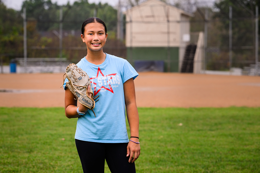 A smiling photo of Arielle with on a softball glove on. 