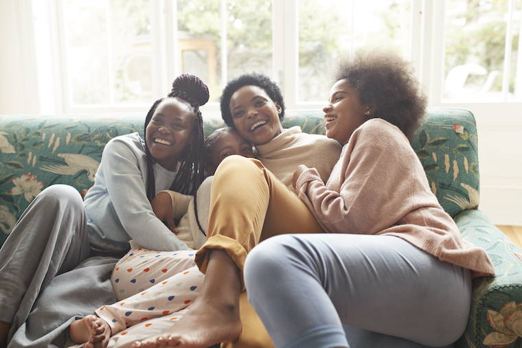 Mom laughing with daughters on the couch