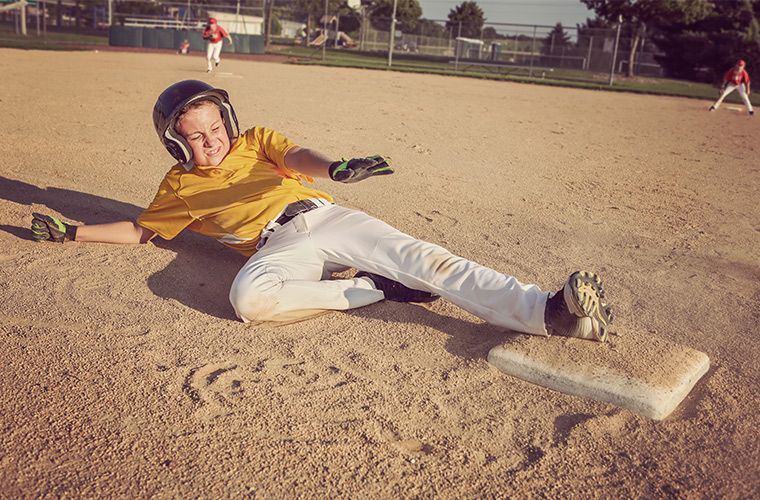 Fotó egy fiatal baseballjátékosról, amint becsúszik a második bázisra.