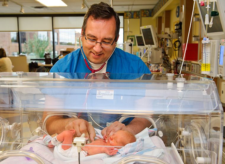 Photo of Dr. John Pardalos caring for an infant in the NICU.