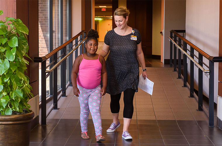 Photo of employee and young girl walking at Women's and Children's Hospital.