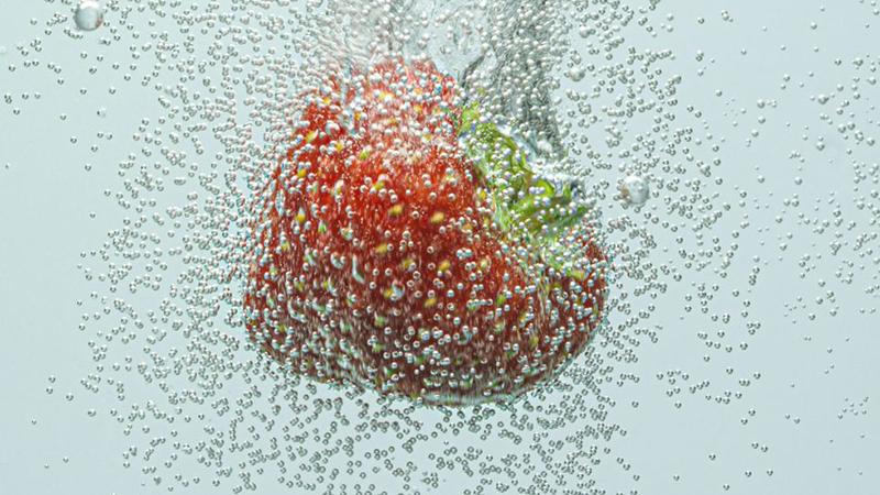 strawberry falling in fizzy water