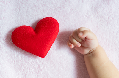 Baby hand reaching for stuffed heart toy