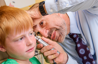 Young boy getting ears examined by doctor