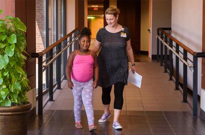 Young girl with woman walking down hallway