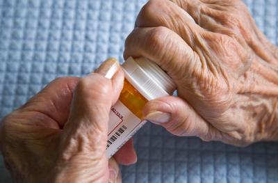 elderly person opening a pill bottle