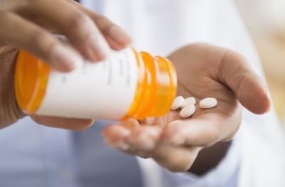 person pouring pills from pill bottle