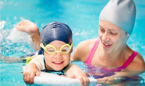 Child learning how to swim with instructor.