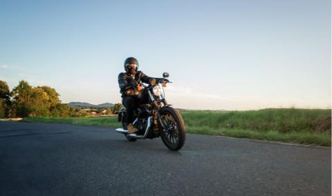 Man sat on motorcycle on the road during sunset. Chopper high power motorcycle goes over landscape.