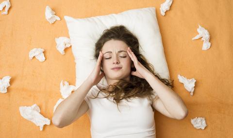 woman with cold surrounded by tissues