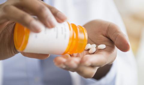 person pouring pills from pill bottle