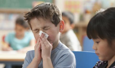 young boy blowing his nose