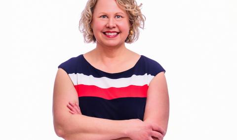 A photo of a woman, smiling with her arms crossed.