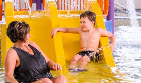 A mother and son playing on a water slide.