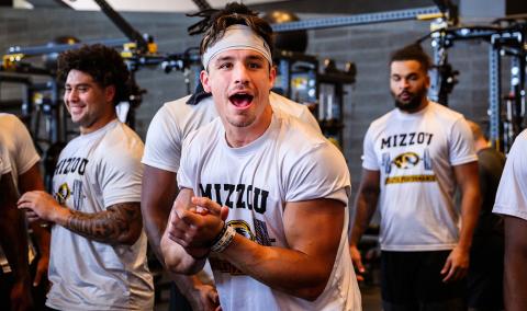Logan Muckey flexing in the weight room with teammates.