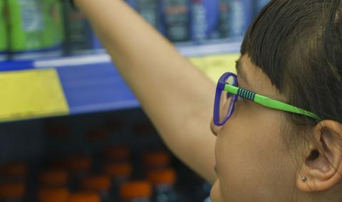 A child reaching for an energy drink at the grocery store.