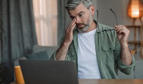 A man rubs his eyes after removing his glasses.