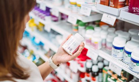 A woman is examining the label of some supplements.