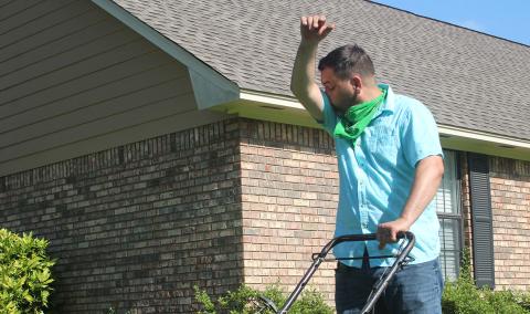 A man sneezing while mowing the lawn.