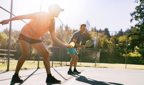People outdoors playing pickleball. 