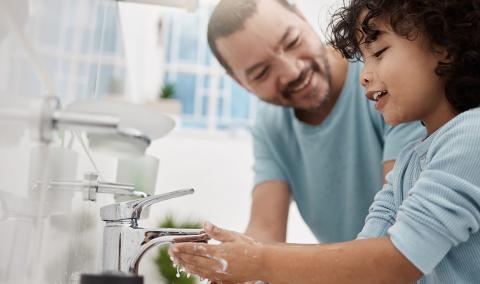 A father teaching his son how to wash his hands.