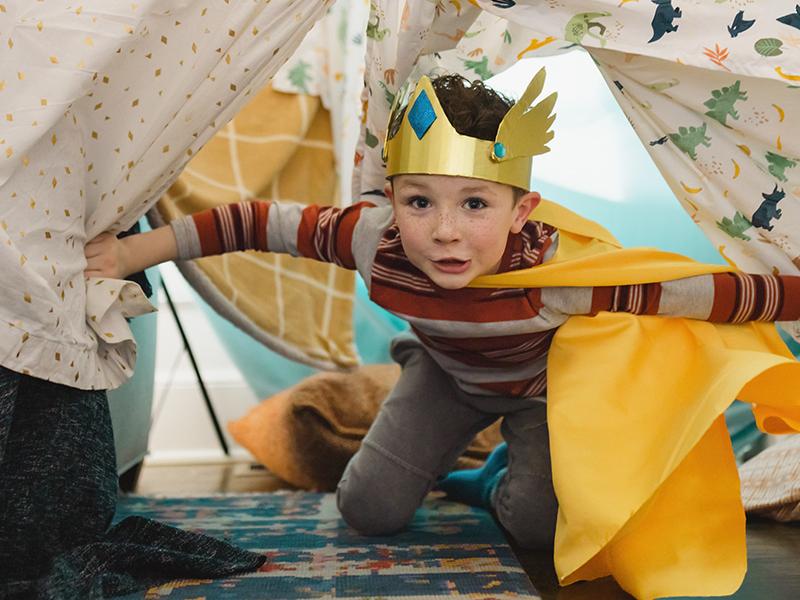 Young boy playing while wearing a cape