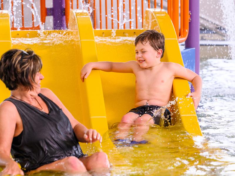 A mother and son playing on a water slide.