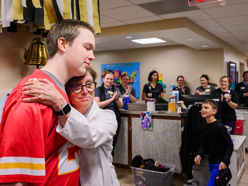 A physician hugging a child after recovering from cancer.