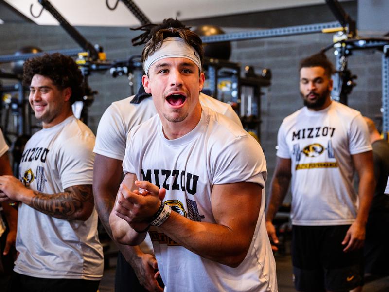 Logan Muckey flexing in the weight room with teammates.