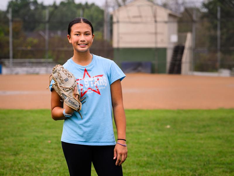 A smiling photo of Arielle with on a softball glove on. 