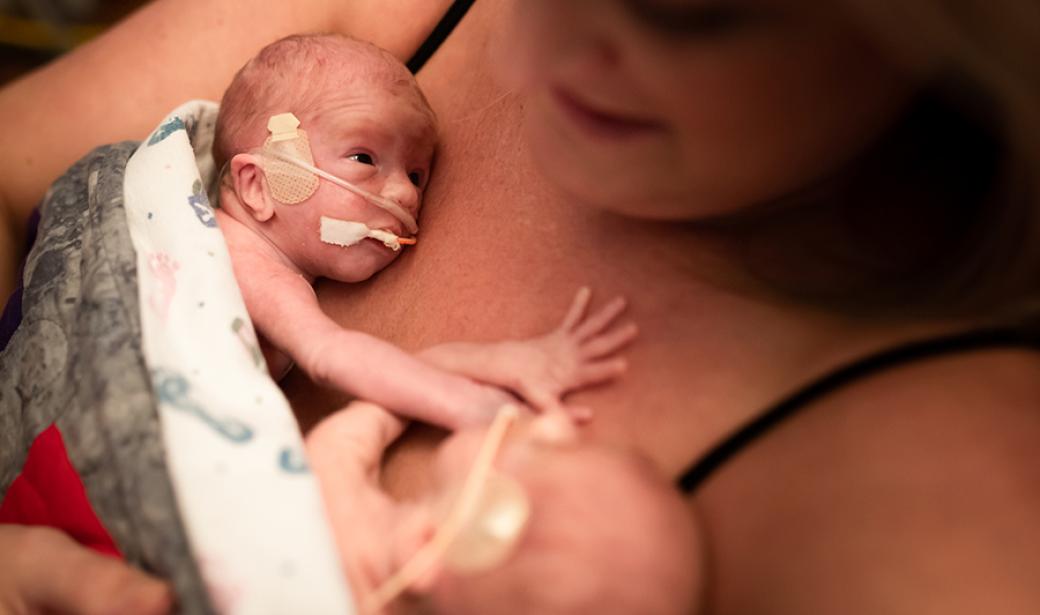 Mother holding twin babies on her chest