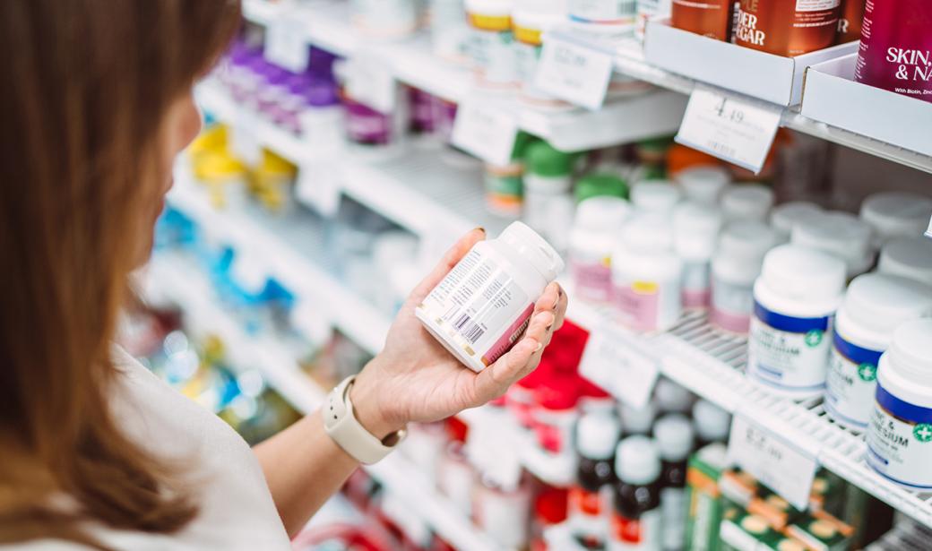 A woman is examining the label of some supplements.