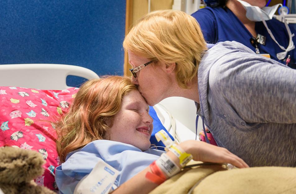 child in hospital bed kissed by mother