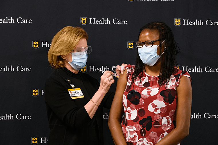 Chief Nursing Officer Mary Beck, DNP, RN, vaccinates pediatric infectious disease specialist Christelle Ilboudo, MD